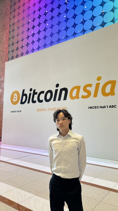 An attendee posing in front of the Bitcoin Asia sign.