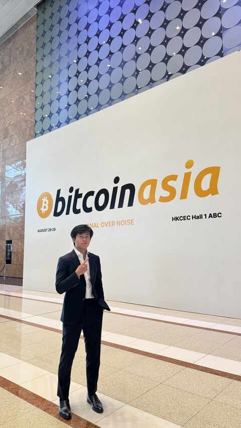 Jason in front of the Bitcoin Asia sign at the Hong Kong Convention and Exhibition Centre.