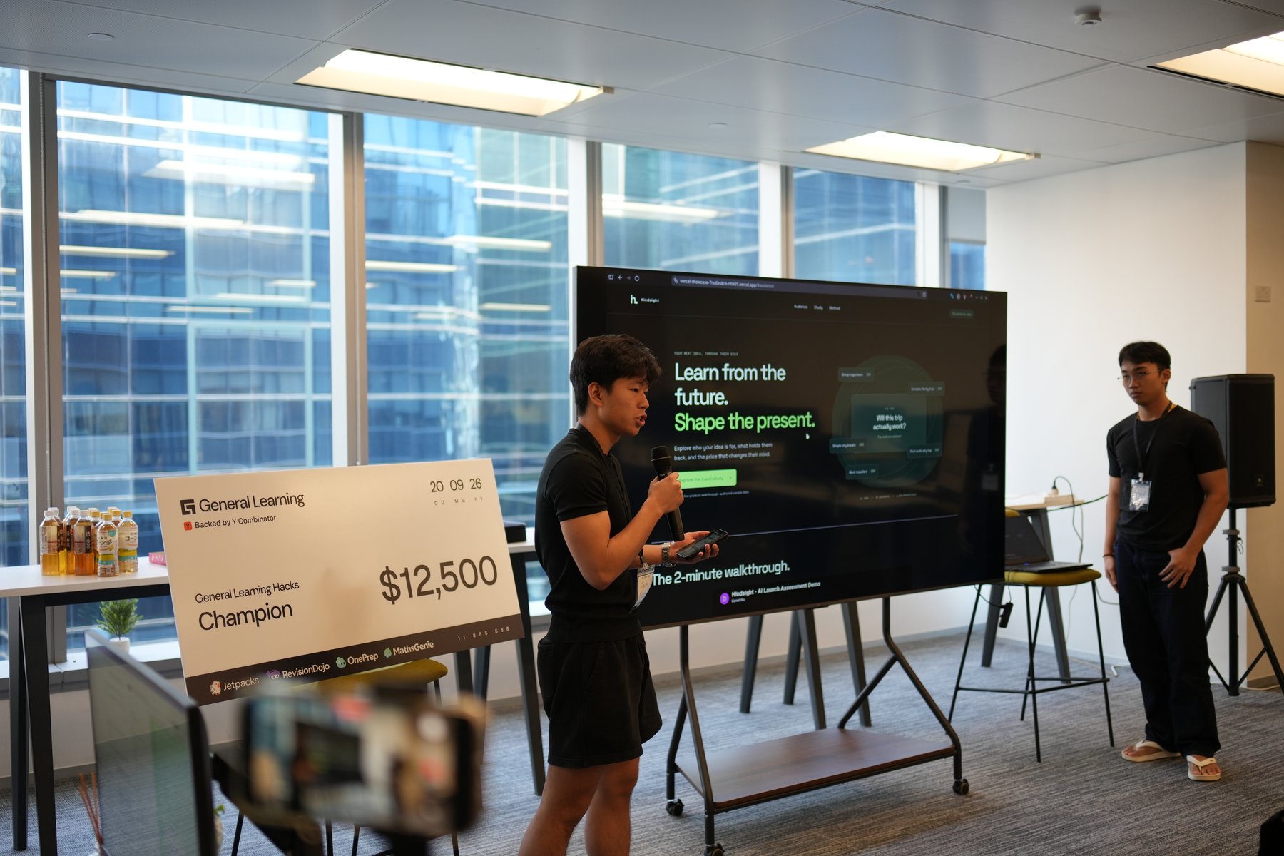 Presenting Hindsight at the General Learning hackathon, with the prototype displayed on a large screen.